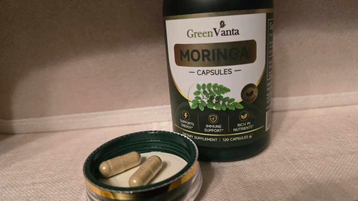 Two GREENVANTA moringa capsules in the bottle cap in front of the bottle